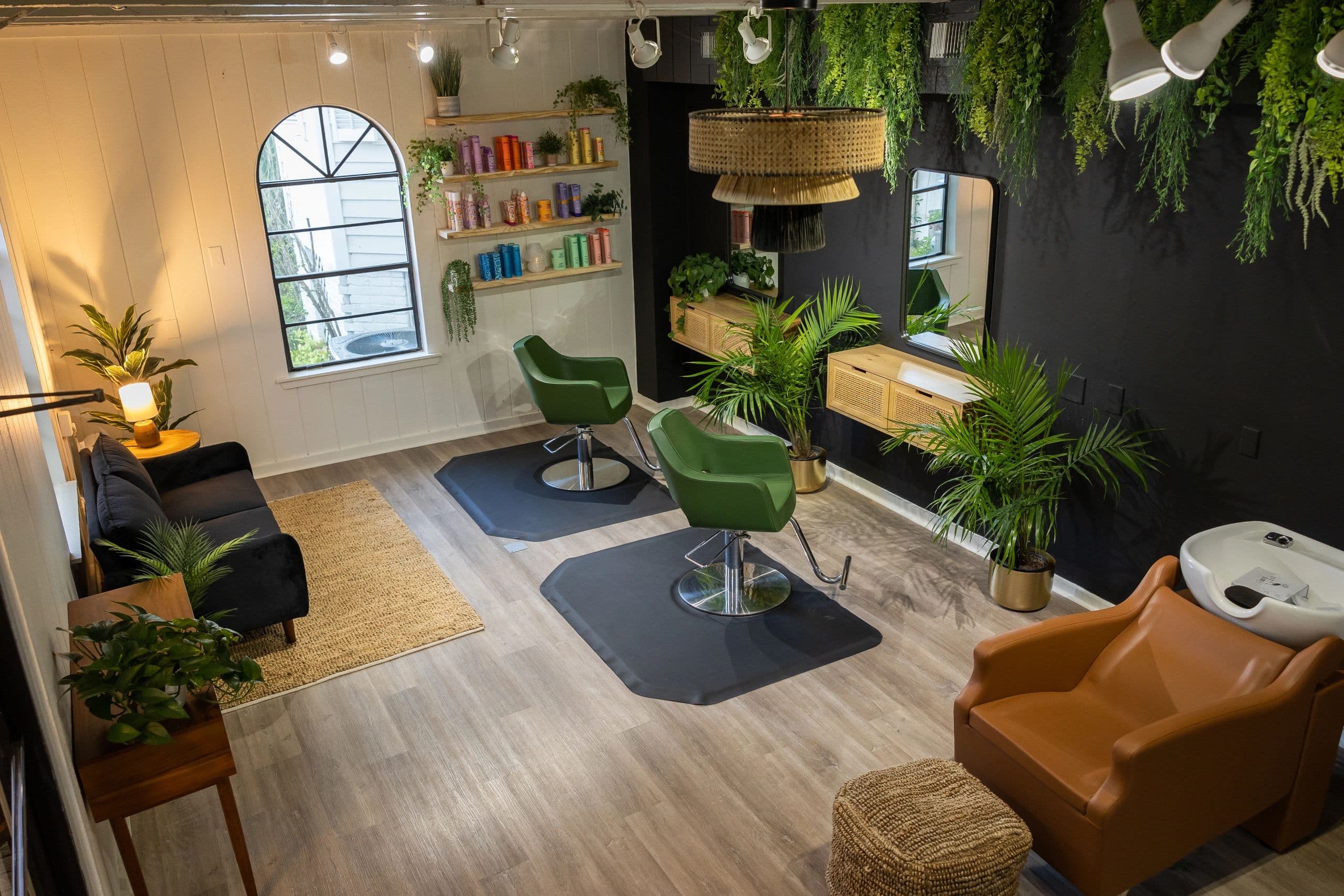 Overhead view of the full salon with styling stations, wash area, and living wall