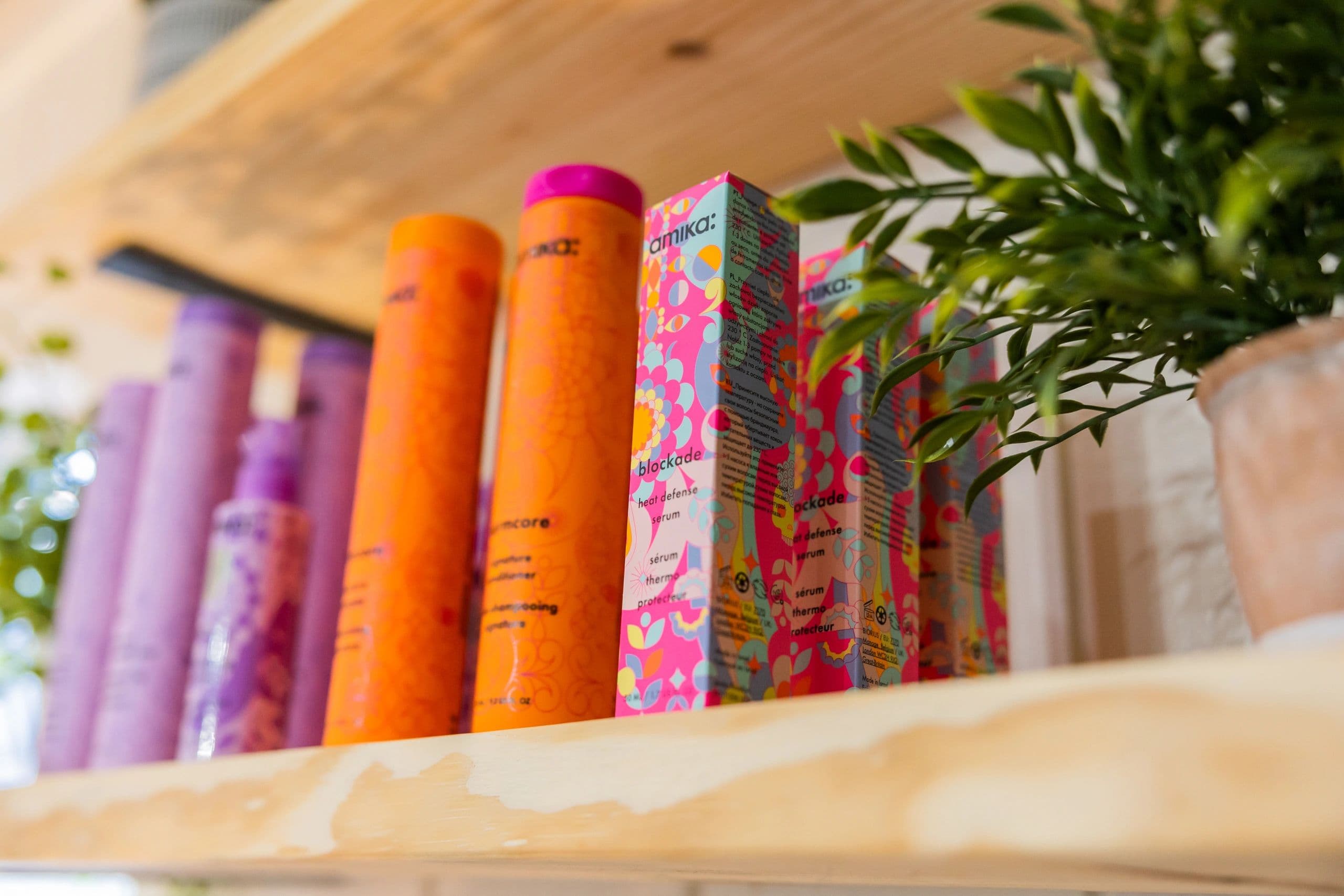 Close-up of colorful Amika hair care products on a wooden shelf